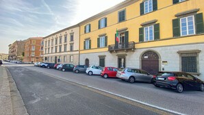 A row of parked cars along a street with yellow buildings and green shutters. - Quiet and Central: Discover Pisa on Foot (Pisa)