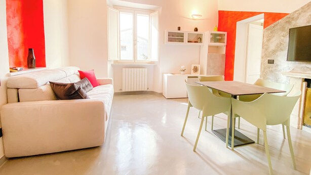 A modern living room with a sofa, a dining table with chairs, a TV, and a window. - Quiet and Central: Discover Pisa on Foot (Pisa)