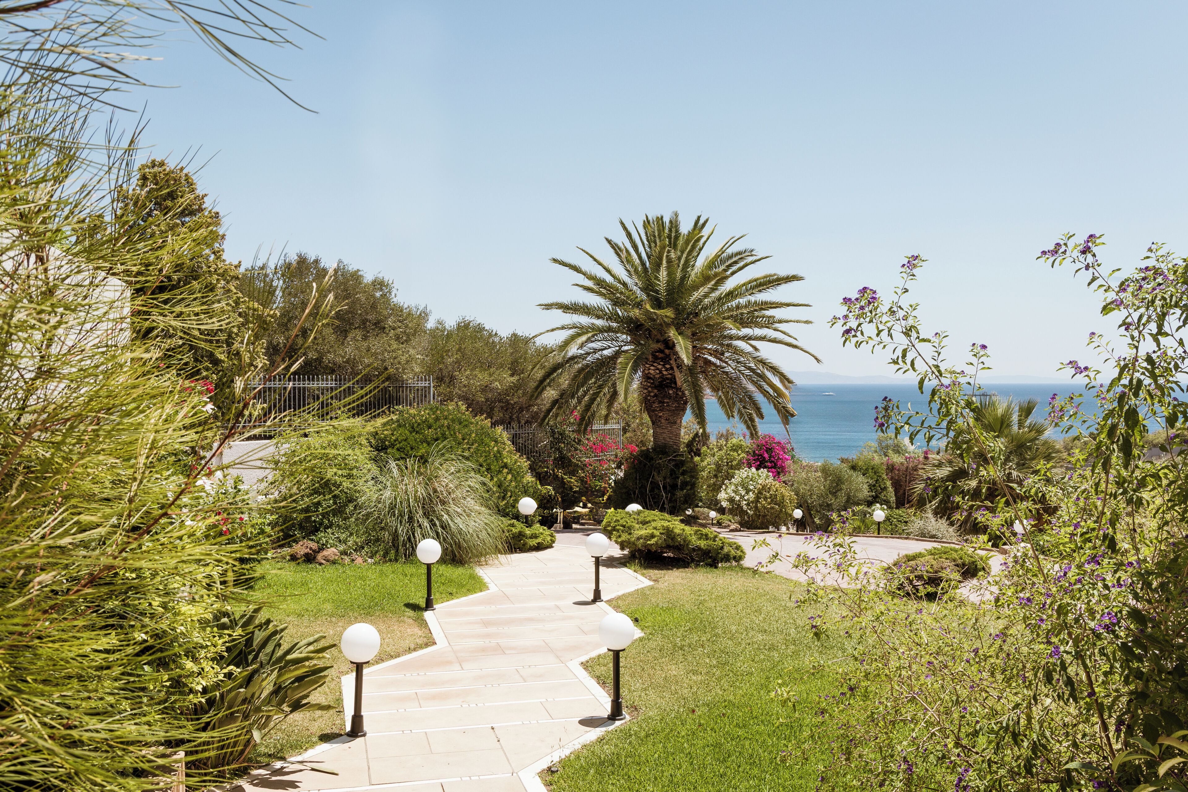 A pathway leading to a building with a view of the sea.