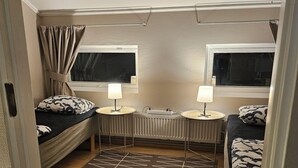 Ein kleines Schlafzimmer mit zwei Betten, einem Heizkörper und zwei Nachttischlampen.