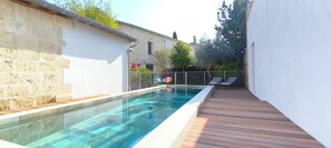 A swimming pool with a wooden deck, stone walls, and a metal fence. - La Grange de Junas. Guest house 80 m2, 4 beds (Junas)