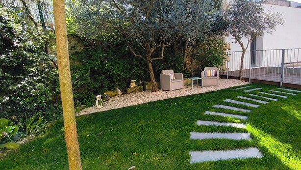 Ein gepflegter Garten mit einem Kiesweg, zwei Sitzbereichen im Freien und einem Schwimmbecken.