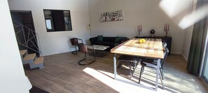 A modern living room with a dining table, a sofa, a chair, and a staircase. - La Grange de Junas. Guest house 80 m2, 4 beds (Junas)