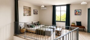A modern living room with a sofa, a dining table, and a staircase.