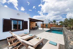 A poolside area with lounge chairs, a wooden deck, a pool, and a dining area. - Vacation Villa 'Andrada' with Private Pool, Wi-Fi and Air Conditioning (Yaiza)