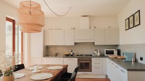 A modern kitchen with white cabinets, a wooden dining table, a hanging light fixture, and a tiled backsplash. - Authentic house with beautiful view of lake como (Musso)