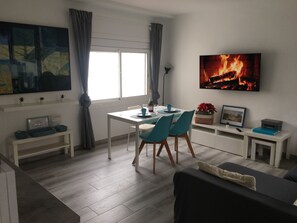 Ein modernes Wohnzimmer mit Essbereich, einem Flachbildfernseher und einem Kamin.