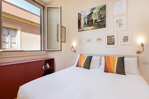 Ein Hotelzimmer mit einem Bett, einem Fenster, einem roten Schrank und Wandbildern.