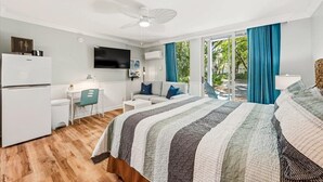 Camera d'albergo con un letto, una scrivania, una sedia, una televisione e una ventola a soffitto.