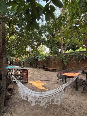A hammock, wooden benches, a pool, and a brick wall in an outdoor setting. - Room-503 Serene Teak Boutique Apartments (Chiang Mai)