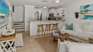 A living room with a sofa, a coffee table, and three bar stools. - Casa Azul- Blue Mountain Beach (Santa Rosa Beach)