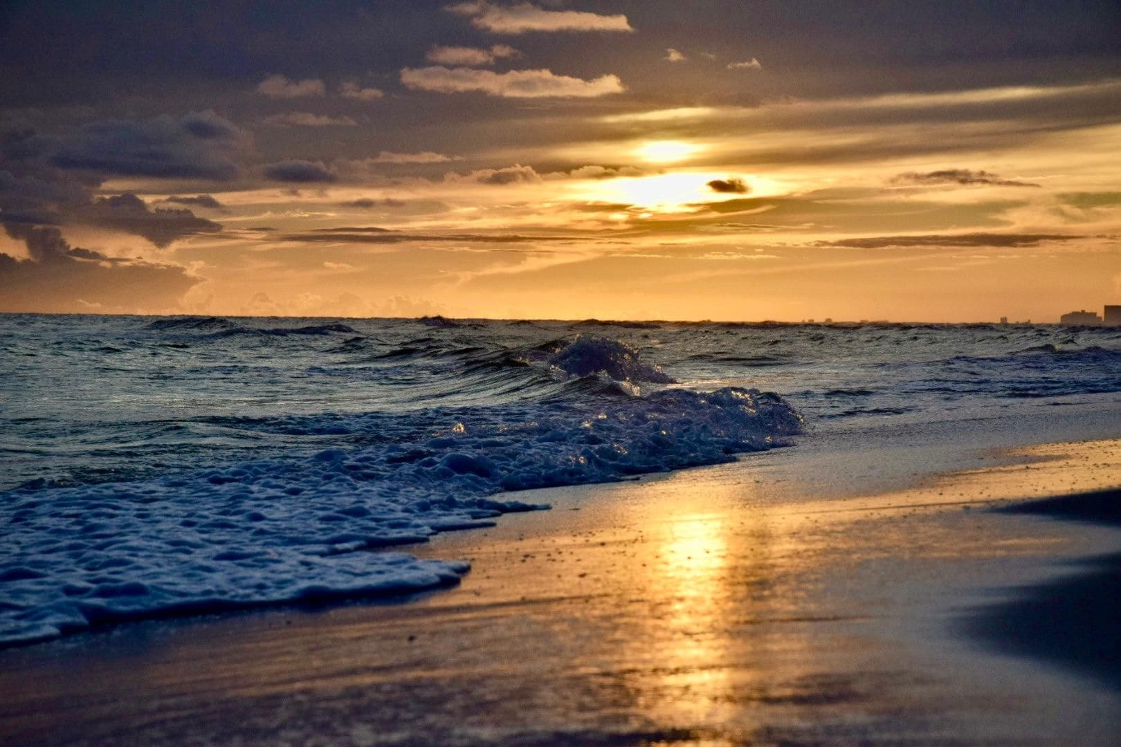 Una playa con olas y un atardecer.