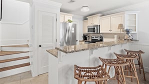A kitchen with white cabinetry, a stainless steel refrigerator, a microwave, and a granite countertop. - Casa Azul- Blue Mountain Beach (Santa Rosa Beach)