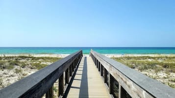 Un paseo marítimo de madera que conduce a una playa con agua turquesa cristalina.