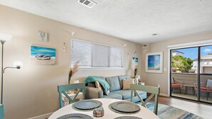 A dining area with a round table, chairs, and a view through a sliding glass door to an outdoor patio. - Cross Creek 29D (Miramar Beach)