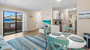 A modern interior with a dining area, kitchen, and sliding glass doors to a balcony. - Cross Creek 29D (Miramar Beach)