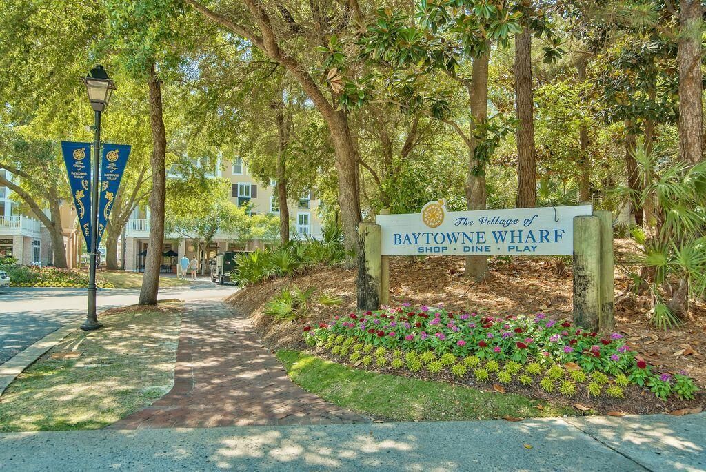 Un letrero de The Village of Baytowne Wharf, con un sendero que conduce a un edificio.