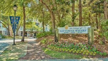 Un letrero de The Village of Baytowne Wharf, con un sendero que conduce a un edificio.