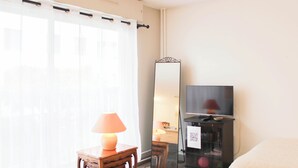 Ein Hotelzimmer mit Bett, Fernseher, Lampe, Tisch und Spiegel.