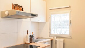 Eine Küche mit Herd, Backofen und einem Fenster mit Blick auf Bäume.