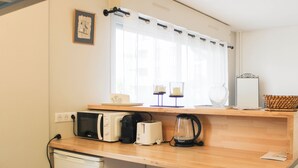 Eine kleine Küche mit Mikrowelle, Toaster, Wasserkocher und einem Kühlschrank.