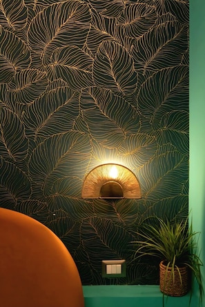 A wall with a leaf-patterned design, a wall-mounted light fixture, and a potted plant. - Apartment Riad Campo de Fiori (Roma)