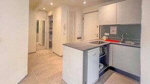 Una cocina compacta con lavavajillas integrado, un lavamanos y una pequeña encimera.