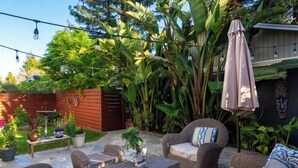 A patio with outdoor furniture, a wooden fence, and lush greenery. - Downtown Mill Valley Vintage Spanish Villa with Beautiful Garden (Mill Valley)
