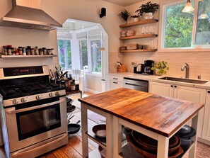 A modern kitchen with an oven, stove, and wooden table. - Downtown Mill Valley Vintage Spanish Villa with Beautiful Garden (Mill Valley)