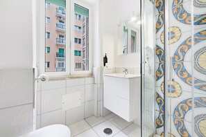 Une salle de bain équipée de toilettes, d’un lavabo, d’un miroir et d’une douche.