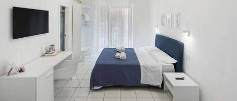 A modern hotel room with a bed, a desk, a TV, and a bathroom.