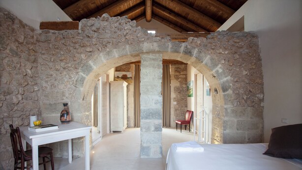 Habitación con paredes de piedra, una cama, una mesa y una silla.