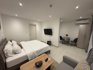 Ein Hotelzimmer mit Bett, kleinem Tisch, Fernseher, Schreibtisch mit Stühlen und Kleiderschrank.