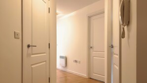 A hallway with white doors, a wall-mounted telephone, and a radiator. - St Johns Courtyard Suite, Bridgnorth with free private parking (Bridgnorth)