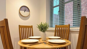A dining table with four chairs, a clock on the wall, and a window with blinds. - St Johns Courtyard Suite, Bridgnorth with free private parking (Bridgnorth)