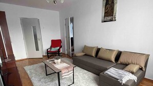 A modern living room with a sofa, a red chair, a coffee table, and a chandelier. - Stunning Panoramic View Last Floor Save (Brasov)