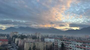 A cityscape with buildings, a parking lot, and mountains in the background.