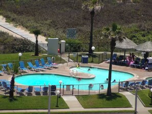 A swimming pool with blue water, surrounded by a fence, and equipped with lounge chairs and umbrellas. - Beachfront Saida condo with Gulf views, resort pools, room for 6 and a $75 beach gear rental credit. (South Padre Island)