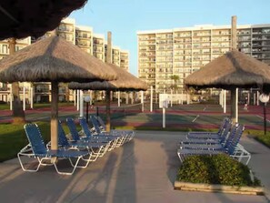 A hotel with a pool area featuring lounge chairs and thatched umbrellas. - Beachfront Saida condo with Gulf views, resort pools, room for 6 and a $75 beach gear rental credit. (South Padre Island)