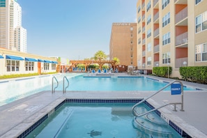 Una piscina con sillones de descanso y una pérgola de madera, rodeada por un edificio de varios pisos con la leyenda 'GULFVIEW II'.