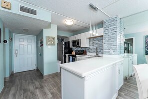 Una cocina moderna con armarios blancos, una isla grande y un salpicadero de azulejos.