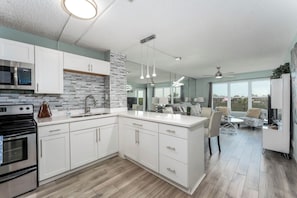 Una cocina moderna con armarios blancos, microondas integrado y una isla grande con pileta.