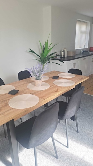 A dining area with a wooden table, black chairs, and a potted plant.