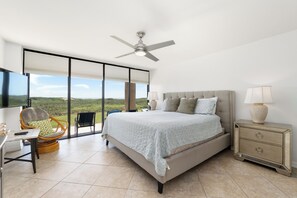 A bedroom with a bed, a nightstand, a chair, a table, and a ceiling fan. - 3BR Beachfront Condo at Sea Vista with Ocean Views (South Padre Island)