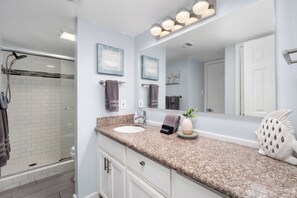 A bathroom with a shower, sink, and vanity. - Beachfront condo with ocean views, pool, hot tub, and private beach access. (South Padre Island)
