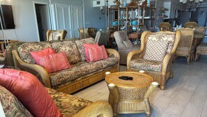 A living room with wicker furniture, a round coffee table, and a television. - Gated beachfront 2BR condo on the 7th floor with stunning Gulf & bay views! (South Padre Island)