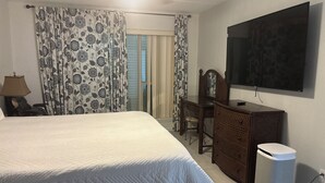 A hotel room with a bed, a desk, a chair, a television, and a waste bin. - Gated beachfront 2BR condo on the 7th floor with stunning Gulf & bay views! (South Padre Island)