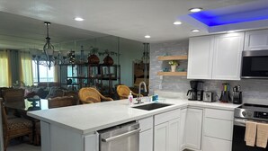 A modern kitchen with white cabinetry, a stainless steel dishwasher, a built-in oven, and a coffee maker. - Gated beachfront 2BR condo on the 7th floor with stunning Gulf & bay views! (South Padre Island)