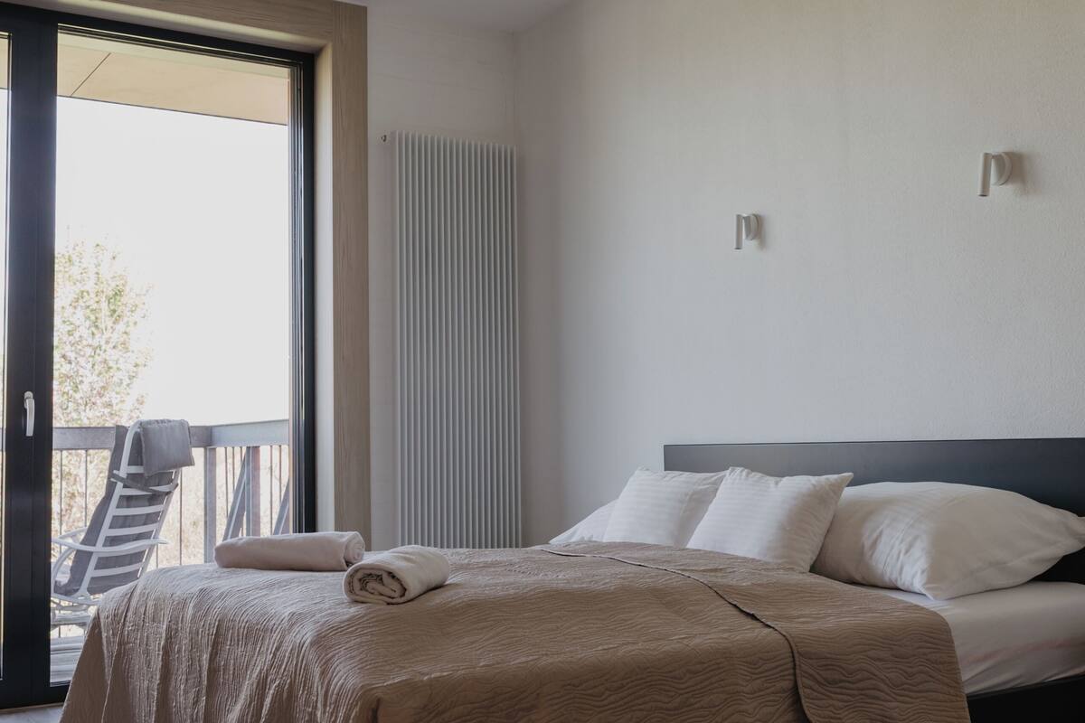 A modern bedroom with a bed, a window, and a view of the outdoors.