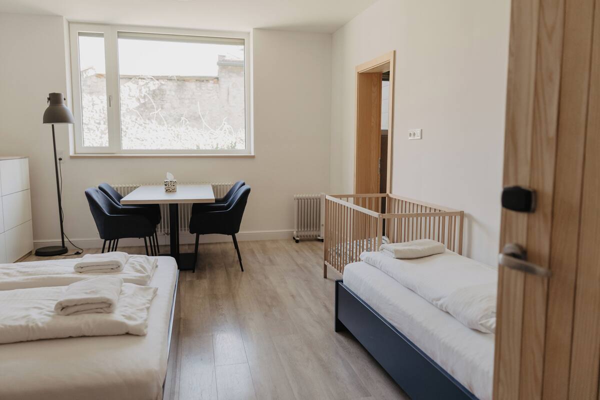 A bedroom with a crib, a desk with chairs, and a radiator.
